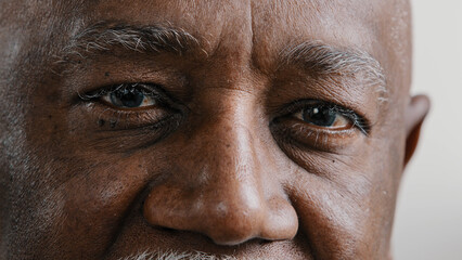 Macro extreme close up half part of face elderly middle-aged African old wrinkled man with dark...