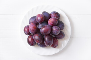 Fresh plum on a plate. White background. View from above.