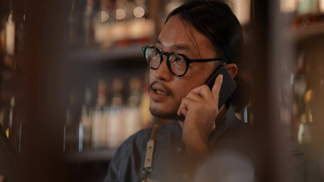 Night club concept of 4k Resolution. The bartender is taking orders from customers with the phone in the restaurant. A group of specialized clubs that sell alcoholic beverages.