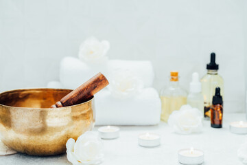 Obraz na płótnie Canvas Spa and wellness massage kit with Tibetan singing bowl. Asian relaxing spa procedure with essential oils and sound healing therapy. Alternative medicine and body care. Selective focus, copy space