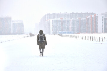 Traveling in winter through a snow-covered city, a young man in winter against the background of a snow-covered city.