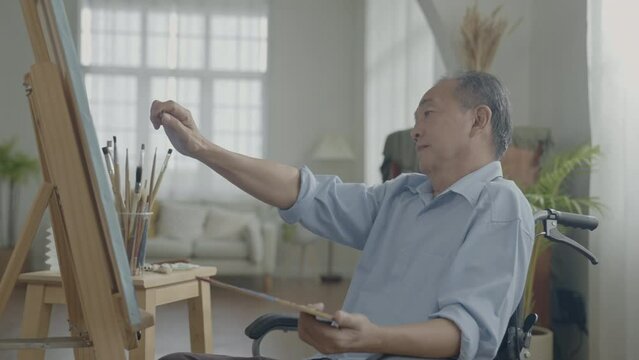 Artist concept of 4k Resolution. Asian man painting in the living room. Artist is creating work. Leisure activities and hobbies.