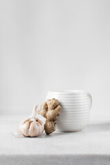Ginger and garlic beside a white cup, ginger and garlic for herbal tea