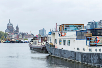 Pleasure ships on a canal in Amsterdam on a cloudy day. Traditions and tourism. © Анна Демидова
