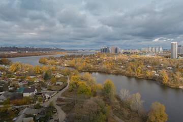 Obraz premium Beautiful panorama of autumn Kiev. View from the left bank to the Dnieper. Wide river in the city and autumn yellow trees.Village and city