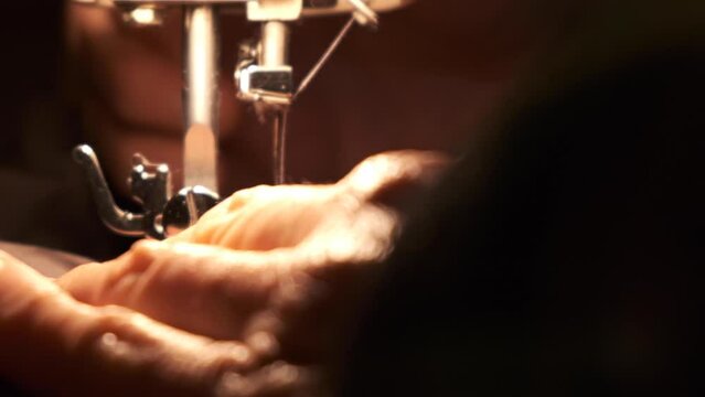 sewing machine Needle in motion. close-up of sewing machine needle quickly moves up and down. Old woman working. The process of sewing the fabric.
