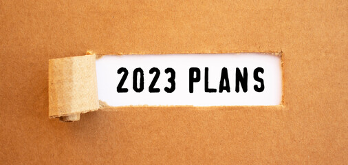 Text 2023 PLANS appearing behind torn brown paper.