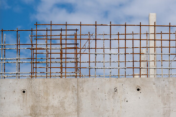 Interessantes Detail einer halbfertigen Stahlbetonmauer auf einer großen Baustelle mit blauem Himmel und selektivem Fokus