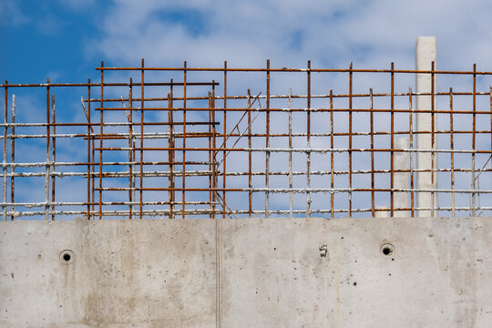 Interessantes Detail einer halbfertigen Stahlbetonmauer auf einer gro&szlig;en Baustelle mit blauem Himmel und selektivem Fokus
