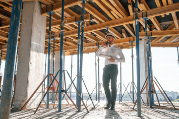 Beautiful sunlight. Walking with plan in hands. Man is working on the construction site at daytime
