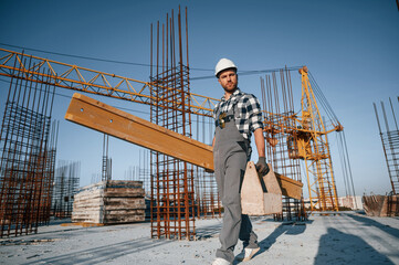 With toolbox and wooden plank. Man is working on the construction site at daytime