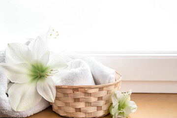 Spa composition with lily flowers and towels in a basket.