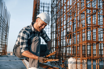 Working with metal material. Man is on the construction site at daytime