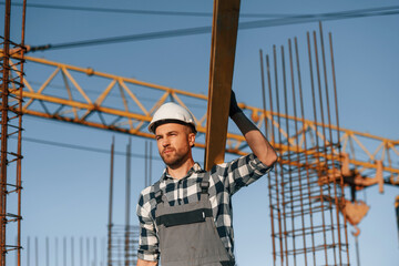 Against crane. With wooden plank. Man is working on the construction site at daytime