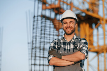 Happy worker is standing on the construction site at daytime