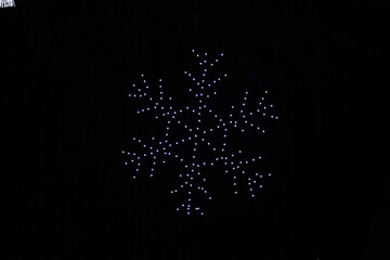 A drone lightshow arranged in the shape of a snowflake
