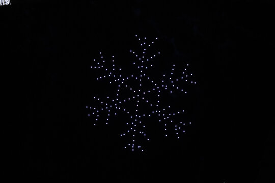 A drone lightshow arranged in the shape of a snowflake