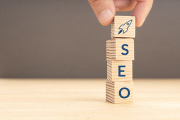 SEO or search engine optimization concept. Hand holding a wooden block with rocket icon and SEO word. Copy space