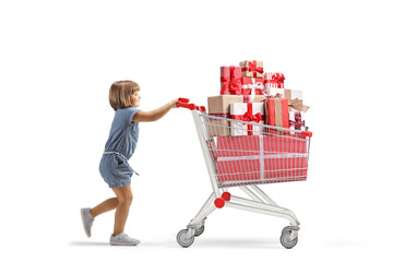 Full length profile shot of a little girl pushing a big shopping cart with presents