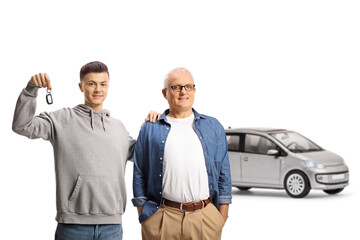 Happy father and son showing a key and standing in front of a silver car