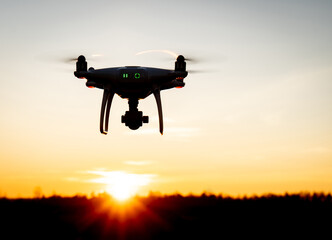 Eine Drohne fliegt in den Sonnenuntergang, Gegenlichtaufnahme.