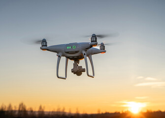 Fototapeta na wymiar Eine Drohne fliegt in den Sonnenuntergang, Gegenlichtaufnahme.