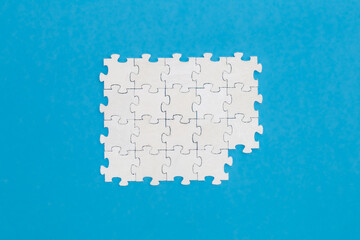 White puzzles on a blue background, flat lay.