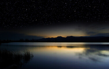 Last light of dusk over a lake surrenders to a starry sky