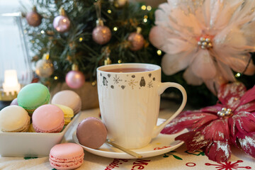 Christmas table decoration with Christmas tree, macaroons, hot tea and a pink angel