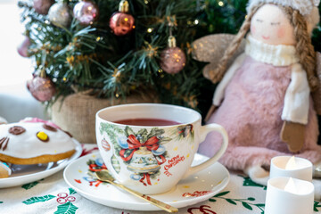 Obraz na płótnie Canvas Christmas table decoration with Christmas tree, macaroons, hot tea and a pink angel