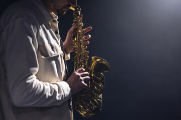 Saxophone in the hands of a man on a dark background, copy space.