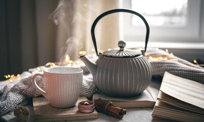 Cozy composition with a teapot, a cup and a book on a blurred background.