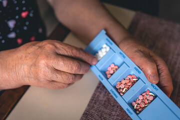 Pills in the hands of an old woman, close-up.