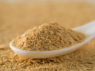 Nutritional yeast background. Nutritional inactive yeast in white spoon. Copy space. Nutritional yeast is vegetarian superfood with cheese flavor, for healthy diet