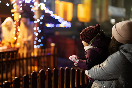 Mother With Daughter Against Scene Where The Virgin Mary Gave Birth To Jesus And He Lies In The Cradle Surrounded By People Who Have Come To Celebrate The Nativity Of Christ.