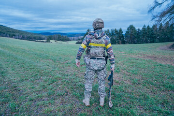 Ukrainian soldier on the front line. With an assault rifle in camouflage. Yellow tape.