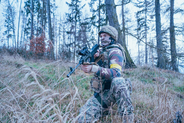 Ukrainian soldier on the front line. With an assault rifle in camouflage. Yellow tape.