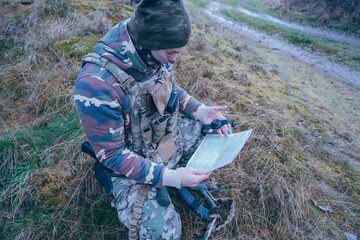 Soldier orients himself according to the map. A soldier works with a map and a compass