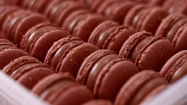 Brown sweet french macaron cakes with chocolate topping in row on the cafe display. Sets of desserts from almond dough and italy merenga in the pastry. Macaroon dessert In bakery shop