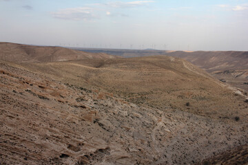 Desert landscape view of sunny rocky cliff with wind turbines in view taken from Shobak Castle, Jordan