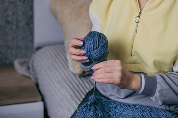 close-up female hands hold a ball of yarn in their hands and unravel an old knitted product