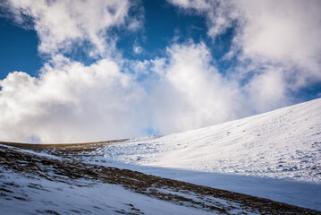 Snowy mountain with clouds and sunshine.