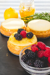 Cheesecakes with berries. Decorating mini cheesecakes with orange marmalade and fresh raspberries and blackberries