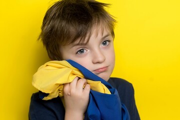 little Ukrainian boy hugs the flag of his country