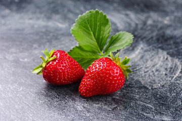 Reife rote Erdbeeren aus biologischem Anbau angeboten als close-up auf einem grauen Board mit Textfreiraum 