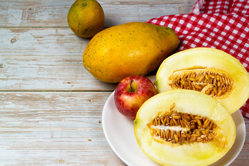 Table of fruits. Melon, papaya, and slices of apple on a wooden table. Selective focus, top view.
