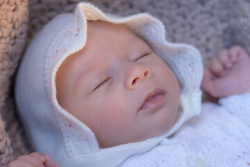 Fototapeta na wymiar beautiful portrait of adorable mixed ethnicity Asian Caucasian baby girl a few weeks old lying on baby cart sleeping peacefully wearing a sweet hat in new life and newborn concept