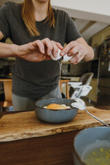 Woman's hands breaking egg for cooking pastry.