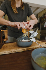 Woman's hands breaking egg for cooking pastry.