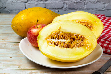 Table of fruits. Melon, papaya, and slices of apple on a wooden table. Selective focus.